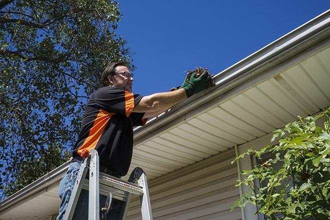 home maintenance worker repairing a leaky gutter in Beverly, MA